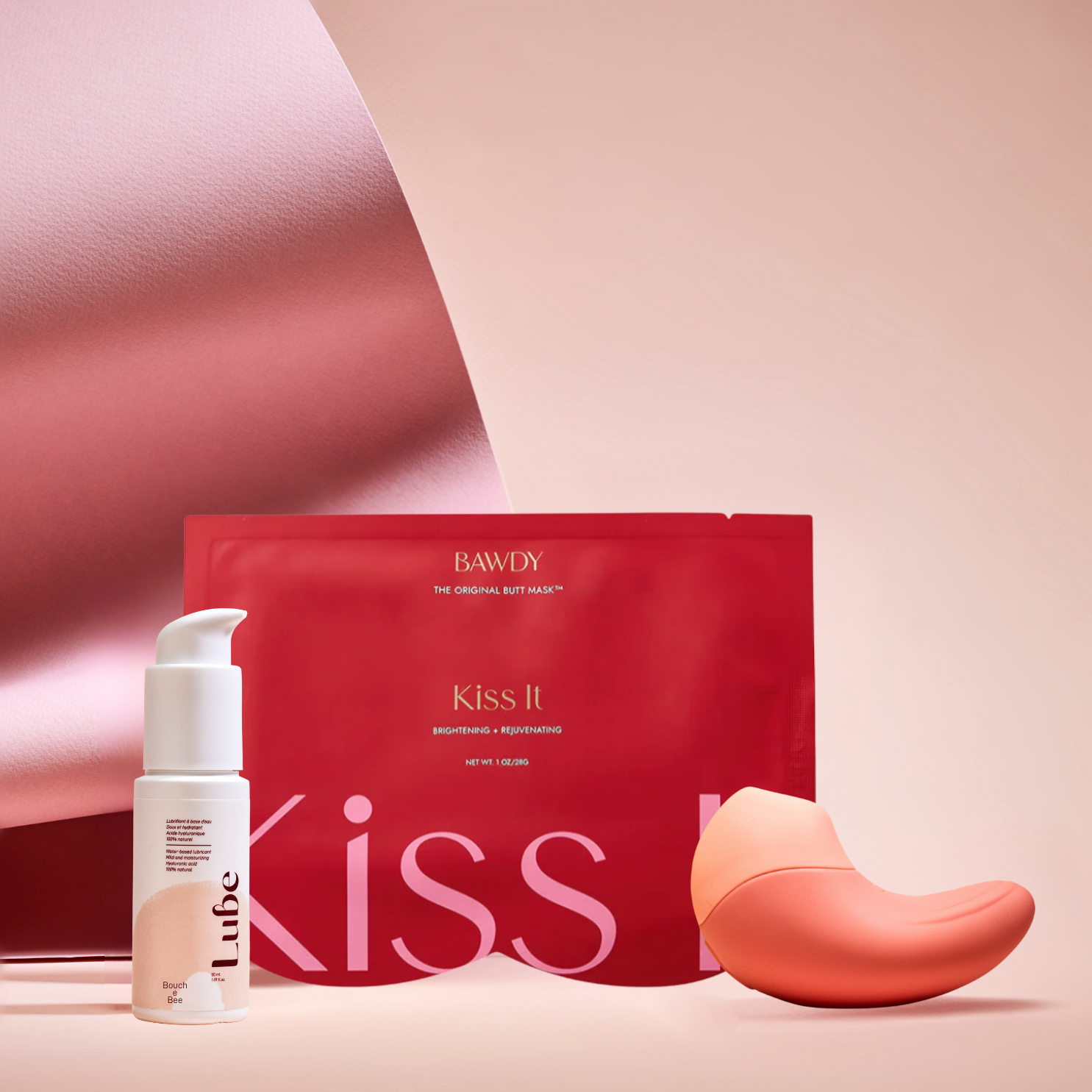 C'est une photo du coffret Badass avec Ona, stimulateur clitoridien vibrant de Bouche Bée, Lube, le lubrifiant 100% naturel à l'acide hyaluronique, le butt mask collection 4 masques de Bawdy, rouge, packaging posé sur des fesses