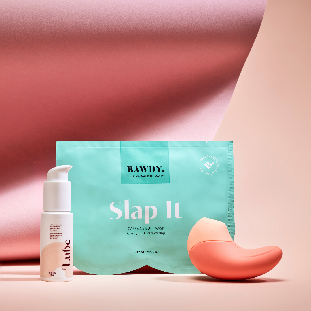 This is a photo of the Badass set with Ona, the vibrating clitoral stimulator from Bouche Bée, Lube, the 100% natural lubricant with hyaluronic acid, the butt mask collection 4 masks from Bawdy, yellow, packaging placed on the buttocks.