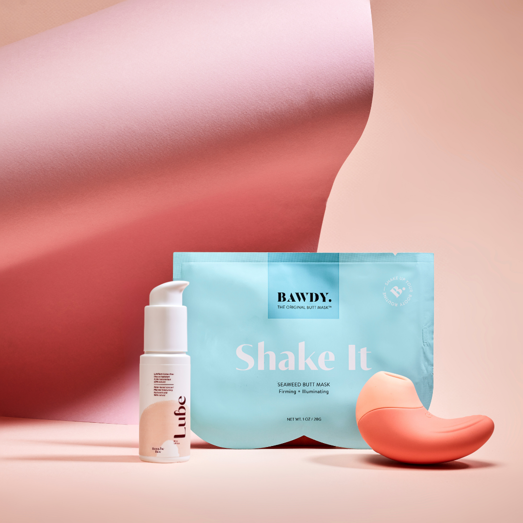 This is a photo of the Badass set with Ona, the vibrating clitoral stimulator from Bouche Bée, Lube, the 100% natural lubricant with hyaluronic acid, the butt mask collection 4 masks from Bawdy, yellow, packaging placed on the buttocks.