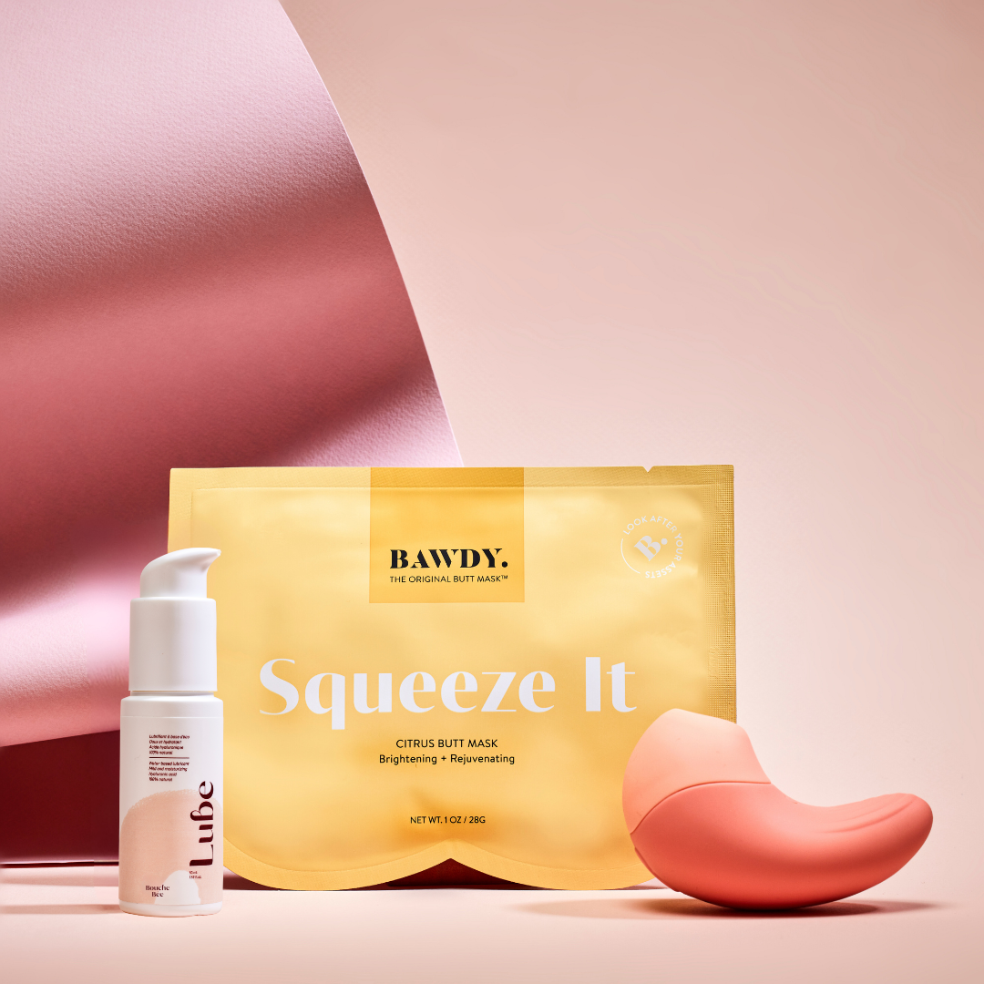 This is a photo of the Badass set with Ona, the vibrating clitoral stimulator from Bouche Bée, Lube, the 100% natural lubricant with hyaluronic acid, the butt mask collection 4 masks from Bawdy, yellow, packaging placed on the buttocks.