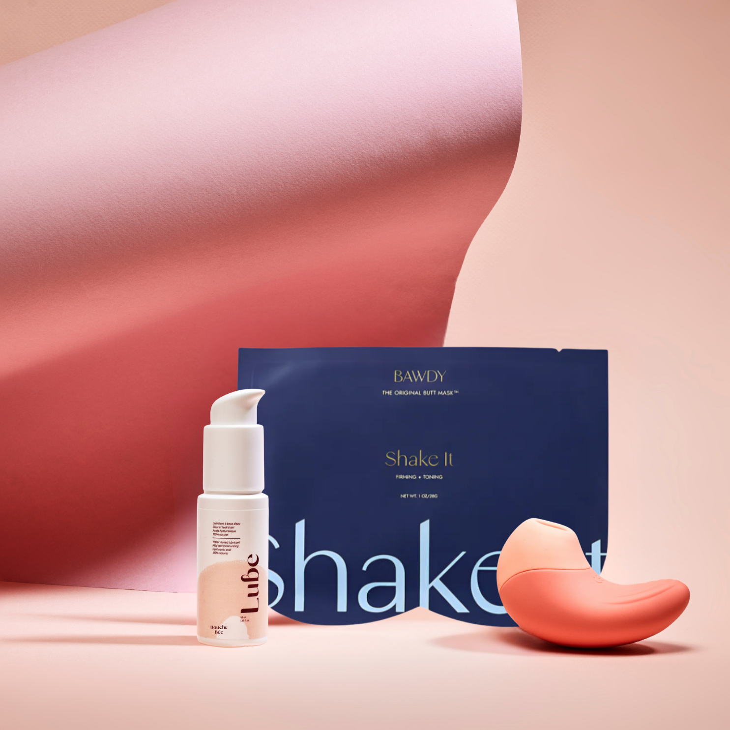 C'est une photo du coffret Badass avec Ona, stimulateur clitoridien vibrant de Bouche Bée, Lube, le lubrifiant 100% naturel à l'acide hyaluronique, le butt mask collection 4 masques de Bawdy, Bleu foncé, packaging posé sur des fesses